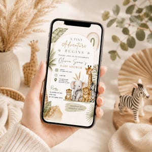 Puede incluir: Una pantalla de smartphone que muestra una invitaci&oacute;n de baby shower con el texto A Tiny Adventure Begins, Olivia Snow's Baby Shower, con ilustraciones de una jirafa, elefante, le&oacute;n y cebra rodeados de hojas tropicales y un arco&iacute;ris.