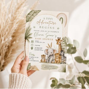Puede incluir: Una tarjeta de invitaci&oacute;n rectangular para baby shower con ilustraciones en acuarela de un leopardo, elefante, le&oacute;n y cebra rodeados de hojas de palma tropicales y un arco&iacute;ris. El texto dice A TINY ADVENTURE BEGINS, OLIVIA SNOW'S BABY SHOWER.