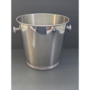 May include: A stainless steel wine bucket with two small handles on the sides. The bucket has a polished finish and two decorative rings near the base. The bucket is designed to hold a bottle of wine or champagne.