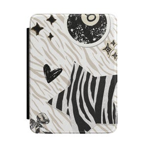 May include: A rectangular e-reader case featuring a cream-coloured background with a light beige zebra stripe pattern. The design includes a black eight ball, a large star with black and white zebra stripes, a black heart, small stars, and a bow.