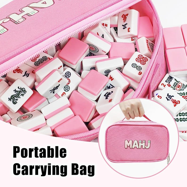 May include: A pink portable carrying bag filled with white and pink Mahjong tiles. The bag is open, revealing the tiles inside. The bag has a zipper and a handle. The text "MAHJ" is on the bag.