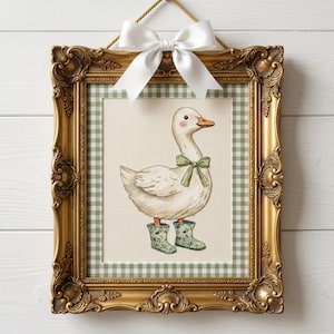 May include: A framed cross-stitch of a white goose wearing a green bow and floral rain boots. The artwork is set against a green and white gingham background and framed in an ornate gold frame, topped with a white bow.