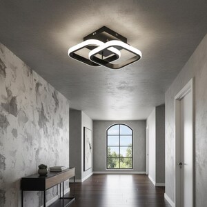 Könnte beinhalten: Moderne schwarz-weiße Deckenleuchte mit quadratischem Design. Die Leuchte hat eine schwarze Basis und zwei ineinandergreifende quadratische Rahmen mit hellem weißem LED-Licht. Die Leuchte ist an einer grauen Decke in einem Flur montiert.