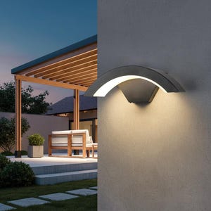 Pode incluir: Uma moderna luminária de parede para exterior com uma sombra curva de metal cinza escuro e uma luz LED branca brilhante. A luz é montada em uma parede cinza, iluminando a área circundante. A imagem mostra um pátio com uma pérgola de madeira e mobiliário de exterior.