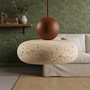 May include: A modern pendant light fixture featuring a light beige, porous stone shade and a dark brown wooden sphere. The fixture hangs from a brown cord, creating a natural and contemporary aesthetic. The light is designed for indoor use.