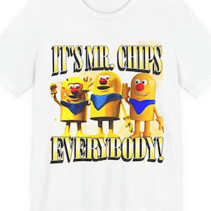 May include: White t-shirt featuring the phrase "IT'S MR. CHIPS EVERYBODY!" in yellow and black. The design includes three cartoon characters with yellow bodies, blue capes, and red noses, each in a different pose.