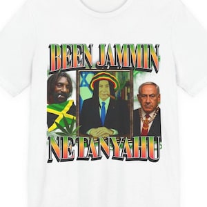Pode incluir: Camiseta branca com um design gráfico. O design inclui o texto "BEEN JAMMIN" acima de três retratos emoldurados. Os retratos apresentam um homem com dreadlocks, um homem com um charuto e um homem com uma corrente de ouro. O texto "NETANYAHU" está abaixo.
