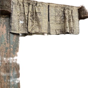 May include: A brown and beige patterned valance with a gathered top and a rod pocket. The valance is hanging on a wooden rod.