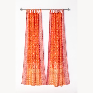 May include: A pair of orange and pink patterned curtains with a white background. The curtains are hung on a silver curtain rod.