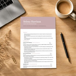 Può includere: Un documento di curriculum stampato per Selena Harrison, una dinamica Senior Marketing Strategist, con un'intestazione color malva, corpo del testo bianco e sezioni di esperienza professionale, su una superficie in legno con una penna nera e una graffetta.