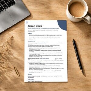 Può includere: Un curriculum vitae intitolato "Sarah Chen" su una scrivania di legno, con un laptop, una tazza di caffè, una penna e una graffetta. Il curriculum vitae descrive l'esperienza nel marketing e include competenze e istruzione.