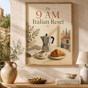 Könnte beinhalten: Ein gerahmter Kunstdruck mit dem Titel The 9 AM Italian Reset, der eine silberne Mokkakanne, eine Tasse Kaffee und ein Croissant auf einem Tisch zeigt, mit Blick auf eine italienische Stadt im Hintergrund und einer Zeitung auf der Seite.