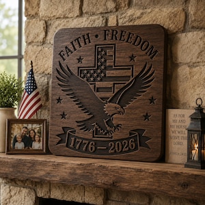 May include: A dark wood sign with the words "FAITH FREEDOM" and the dates "1776-2026" carved into it. The sign features an eagle, stars, and a cross with the American flag design. The sign is displayed on a wooden mantel.