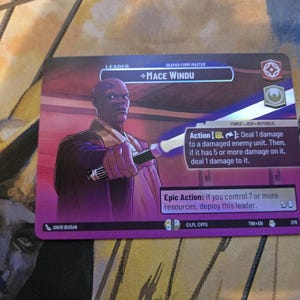 Peut inclure: Une carte à collectionner Star Wars avec Mace Windu, un personnage chauve en tenue violette et marron, tenant un sabre laser. La carte contient du texte, dont "Leader" et "Epic Action". La carte est violette et bordée de blanc.