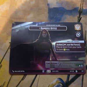 May include: A rectangular card featuring the character Barriss Offee from the Star Wars universe. The card has a dark color scheme with text that reads "Leader" and "We Have Become Villains." The card also includes game instructions and a character illustration.