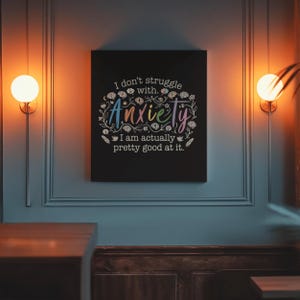 May include: A black canvas art print with the text "I don't struggle with Anxiety. I am actually pretty good at it." The word "Anxiety" is in rainbow colors and surrounded by floral and brain illustrations.