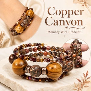 May include: A multi-strand memory wire bracelet featuring large polished wooden beads, speckled brown stone beads, and metallic copper-toned spacers with a Greek key pattern. The design includes smaller dark red and brown glass beads throughout.