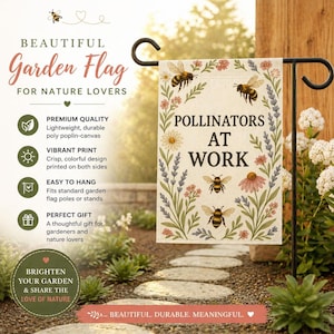 Puede incluir: Una bandera de jardín crema con el texto "Pollinators at Work" e ilustraciones de abejas y flores. La bandera cuelga de un soporte de metal negro. Está diseñada para los amantes de la naturaleza y los jardineros.