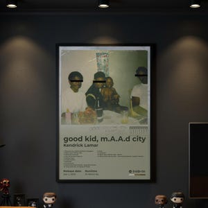 Puede incluir: Un póster enmarcado con la portada del álbum "good kid, m.A.A.d city" de Kendrick Lamar. El póster tiene una estética vintage con una fotografía descolorida de personas. El título del álbum y la lista de canciones se muestran en una fuente minimalista.