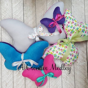 May include: Five handmade butterfly-shaped pillows in various colors and patterns. The pillows are made of felt and fabric and feature bows and ribbons.