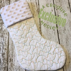 May include: White Christmas stocking with a quilted bone pattern and a soft, textured cuff. The bone outlines are stitched with colorful thread. The text "A Creative Exclusive Medley" is visible on the right side.