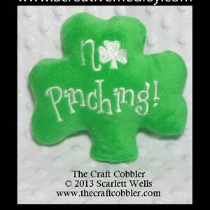 May include: Green shamrock-shaped plush pillow with white embroidery that reads "No Pinching!"