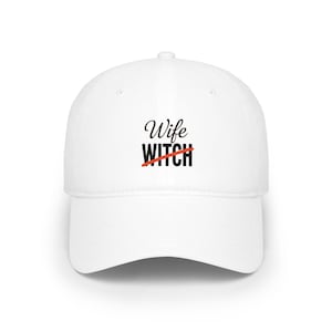 May include: A white baseball cap with a curved brim. The cap features the words "Wife" above "Witch" with a red line through "Witch". The text is in a black, stylized font. The cap is a classic, casual style.