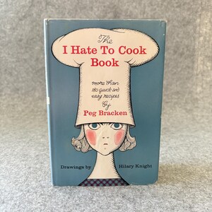 May include: A hardcover book titled The I Hate To Cook Book by Peg Bracken with drawings by Hilary Knight. The blue cover features an illustration of a person wearing a large white chef hat, with text stating it contains more than 180 recipes.