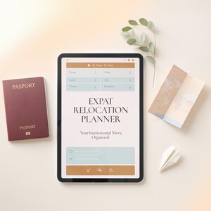 May include: A tablet displaying an Expat Relocation Planner interface with the text Your International Move, Organized, positioned next to a maroon passport, a folded world map, a small paper airplane, and a sprig of eucalyptus leaves.