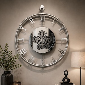 May include: A large, silver-colored wall clock with Roman numerals hangs above a dark wood console table. The clock features a gear-like design in the center. The table holds a lamp, decorative items, and a woven basket. A vase with greenery is on the table.