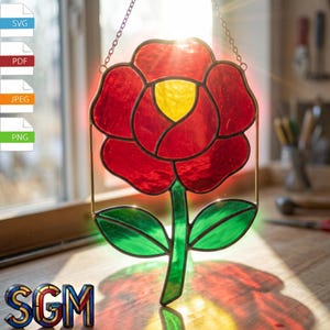 May include: A stained glass rose window featuring red petals and a yellow centre. The flower has green leaves and a green stem. The window is suspended by a chain. The image is illuminated by sunlight.