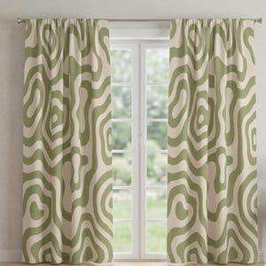Puede incluir: Un par de cortinas verdes y crema con un patrón ondulado orgánico y repetitivo. Las cortinas cuelgan frente a una ventana, agregando un elemento decorativo a la habitación. El diseño recuerda a las líneas topográficas.