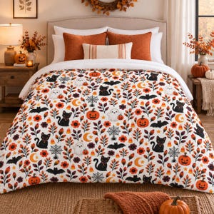 May include: A white bedspread featuring a repeating Halloween pattern of black cats, orange pumpkins, white ghosts, black bats, spider webs, yellow crescent moons, and candy corn, interspersed with orange and brown autumn leaves.