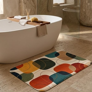 Peut inclure: Un tapis de bain rectangulaire avec un motif abstrait de formes superposées en rouge, orange, jaune, turquoise et vert. Le tapis est posé sur un sol carrelé près d'une baignoire blanche.