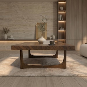 K&ouml;nnte beinhalten: Ein niedriger, rechteckiger Couchtisch aus dunkelbraunem Holz mit ausgepr&auml;gter Maserung. Der Tisch hat eine dicke Tischplatte, die von vier geschwungenen, integrierten Beinen getragen wird, die sich an der Basis treffen und ein durchgehendes Bogendesign bilden.