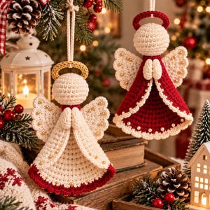 May include: Two crocheted angel ornaments hanging by white cords. One angel is primarily cream with a gold halo and red hem, while the other is primarily red with a red halo and cream hem. Both feature small gold beads on their wings and gowns.