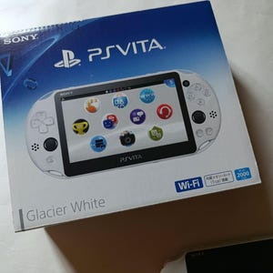 Könnte beinhalten: Eine weiße Sony PlayStation Vita Handheld-Spielkonsole in der Farbe Glacier White. Die Verpackung zeigt das PS Vita-Logo, Wi-Fi-Branding und eine Grafik der weißen Konsole mit einem schwarzen Bildschirm und bunten App-Symbolen.