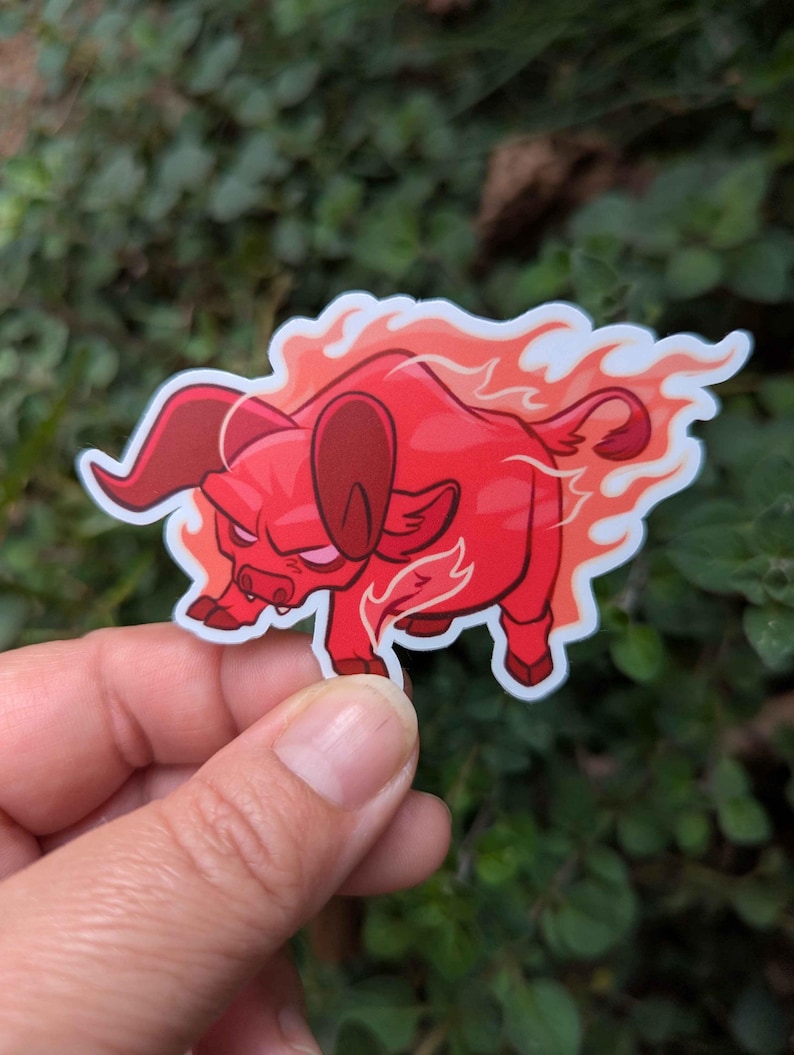 Puede incluir: Una pegatina roja con un toro de dibujos animados con llamas. El toro tiene una expresi&oacute;n feroz y est&aacute; caminando. La pegatina est&aacute; sobre un fondo de follaje verde.