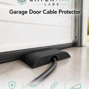 May include: Black garage door cable protector with the text "Garage Door Cable Protector". The protector is designed to protect EV charging cables. Features include a low-profile ramp design and durable PETG material.