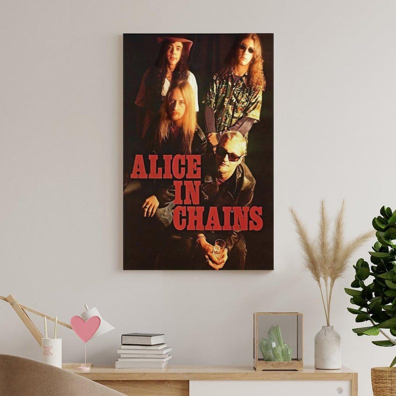Puede incluir: Un p&oacute;ster de pared rectangular que presenta una fotograf&iacute;a oscura y melanc&oacute;lica de la banda de rock Alice in Chains. Los cuatro miembros de la banda aparecen en un retrato grupal con el texto ALICE IN CHAINS en letras rojas may&uacute;sculas.