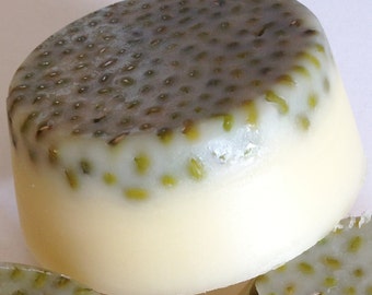 Puede incluir: Una pastilla de jabón redonda y blanca con la parte superior moteada de verde y marrón. El jabón está hecho con ingredientes naturales y es perfecto para pieles sensibles.