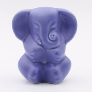 May include: A small, ceramic elephant figurine in a light purple color. The elephant is sitting with its trunk curled up and its eyes closed.