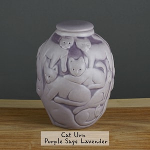 May include: Purple sage lavender ceramic cat urn with a lid and a design of multiple cats in relief.