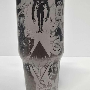 May include: A grey stainless steel tumbler with manga-style illustrations and the words "Solo Leveling." The design includes panels with characters and action scenes. The tumbler has a lid and a straw.
