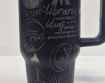 Puede incluir: Taza de viaje negra con diseños grabados y texto, incluyendo "Crescent City", un ciervo y la frase "Light it up". La taza tiene un asa negra, tapa y un interior plateado.