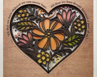 May include: A layered wooden art piece featuring a heart-shaped design filled with flowers and leaves in shades of orange, pink, and yellow. The artwork includes the quote, "All that we have enjoyed we can never lose. All that we love deeply becomes a part of us."