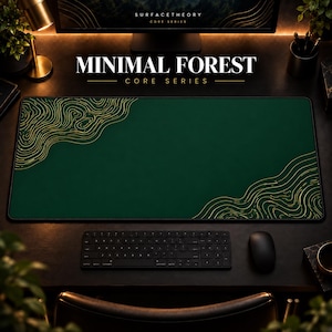 May include: A rectangular desk mat in deep forest green featuring gold-colored topographic line patterns in the top-left and bottom-right corners. The mat is positioned on a dark surface with a black keyboard and mouse nearby.