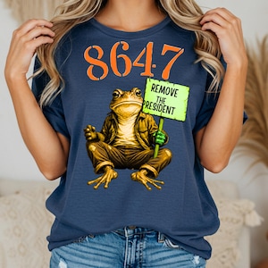 May include: Navy blue t-shirt featuring the orange number 8647. A frog in a jacket and trousers holds a green sign that reads "REMOVE THE PRESIDENT".