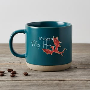 May include: A teal ceramic mug with a matte finish and a light beige base. The mug features a red dragon illustration and the white text "It's been My Honor" printed on the side. The handle is curved and the mug has a smooth, rounded rim.