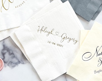 May include: White paper napkins with gold and black calligraphy. One napkin reads "Haleigh & Gregory" with a heart and the date "12-04-2021". Other napkins have names and dates. Ideal for weddings and special events.
